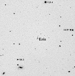 Devant un fond blanc, de nombreux objets noirs sont visibles. Eris est pointée par une flèche.