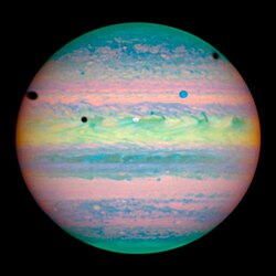 Sur l'hémisphère nord de Jupiter se détachent un disque blanc et un bleuté et trois taches sombres (les ombres portées)