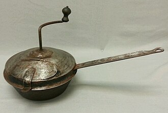 Poêle à long manche avec un couvercle muni en son centre d'une manivelle.
