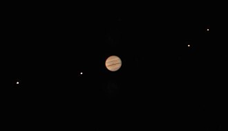 Jupiter est reconnaissable avec ses bandes rouges. Les lunes sont distinguable et non floues mais apparaissent comme des points lumineux.