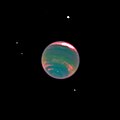 Neptune, entourée de points blancs, a une couleur plus sombre et des structures nuageuses roses sont visibles.