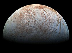 La moitié de la lune est dans la lumière. Des lignes et brunes contrastent avec la surface grisâtre.