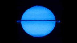 Saturne représentée bleue. Elle tourne sur elle-même et deux cercles brillants apparaissent aux pôles par intermittence.