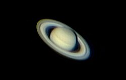 Image peu nette de Saturne où elle est clairement distinguable ainsi que ses anneaux.