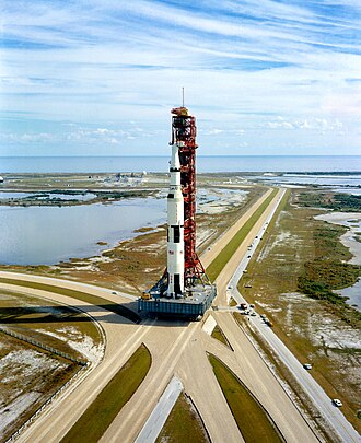 La Saturn V sur sa plateforme de lancement en route pour le pas de tir apparaissant en arrière-plan au loin (Apollo 14, 1970).