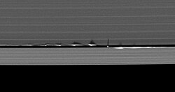 « Vagues » verticales provoquées par Daphnis projetant leurs ombres dans les anneaux de Saturne.