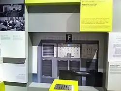 Photo d'une machine avec une console de commandes et des fiches explicatives autour