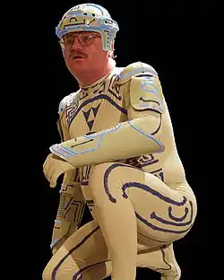 Homme accroupi dans un costume moulant blanc avec des train bleu imitant des connections électriques