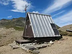 Petite cabane triangulaire dans un paysage montagneux.