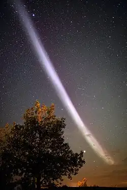 Vue nocturne du ciel traversée par un ruban lumineux aux teintes violettes.